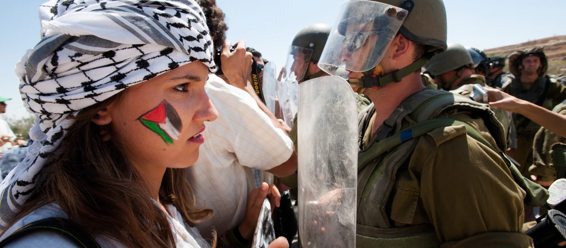 Al-Masara, Occupied Palestinian Territories - August 24, 2012: Italian solidarity activists join Palestinians confronting heavily armed Israeli soldiers in a weekly nonviolent demonstration against the separation barrier that would cut off the West Bank village of Al Ma'sara from its agricultural lands.
